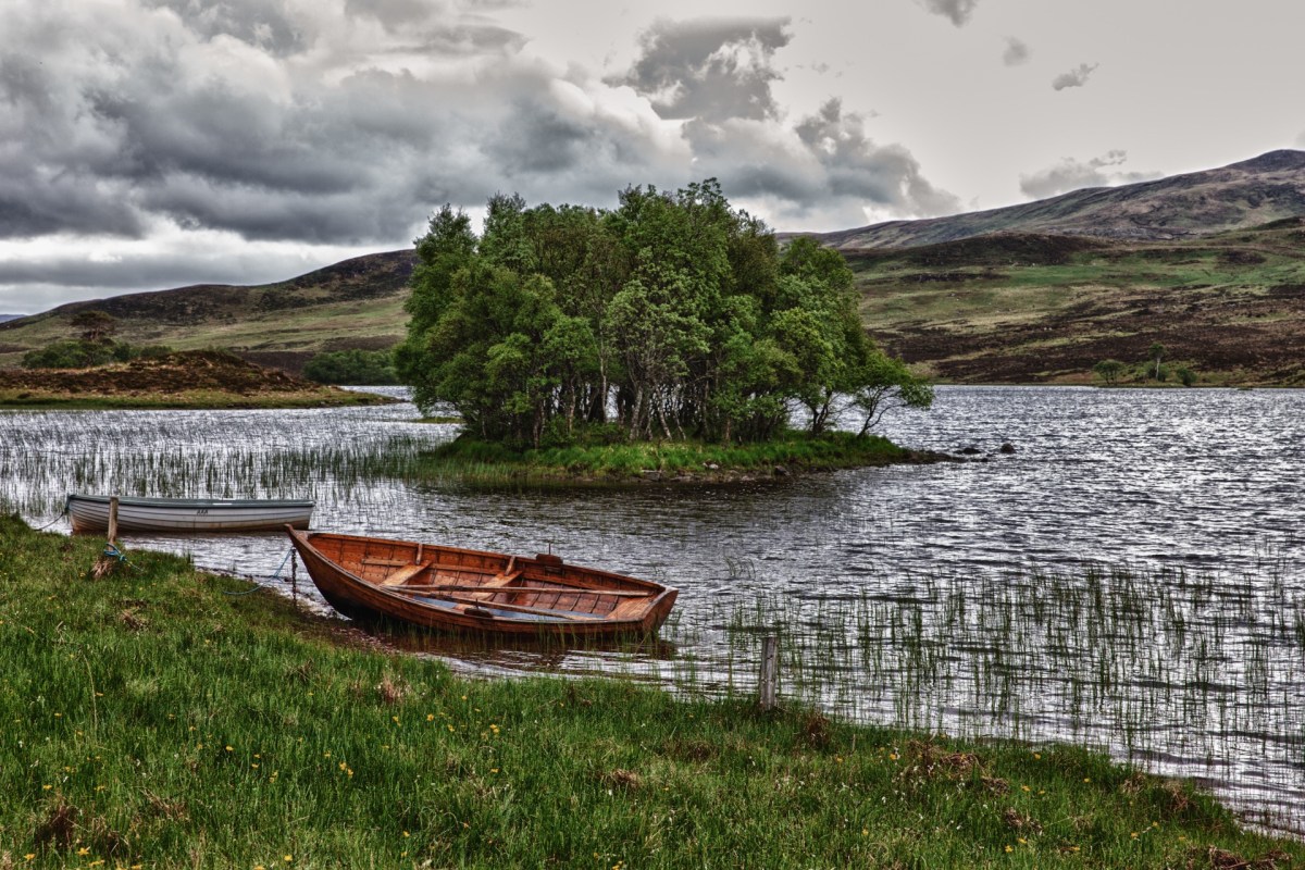 A small lake with a wooded island and two rowboats near the banks